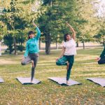 Slim young women are doing variations of Tree pose during yoga class outdoors in park relaxing and enjoying nature and activity. Sports, youth and health concept.